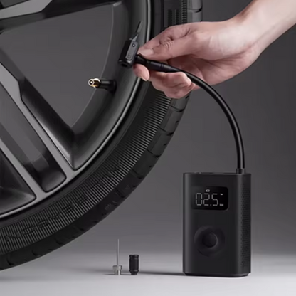 Hand using a digital tire inflator on a car tire with a gray background